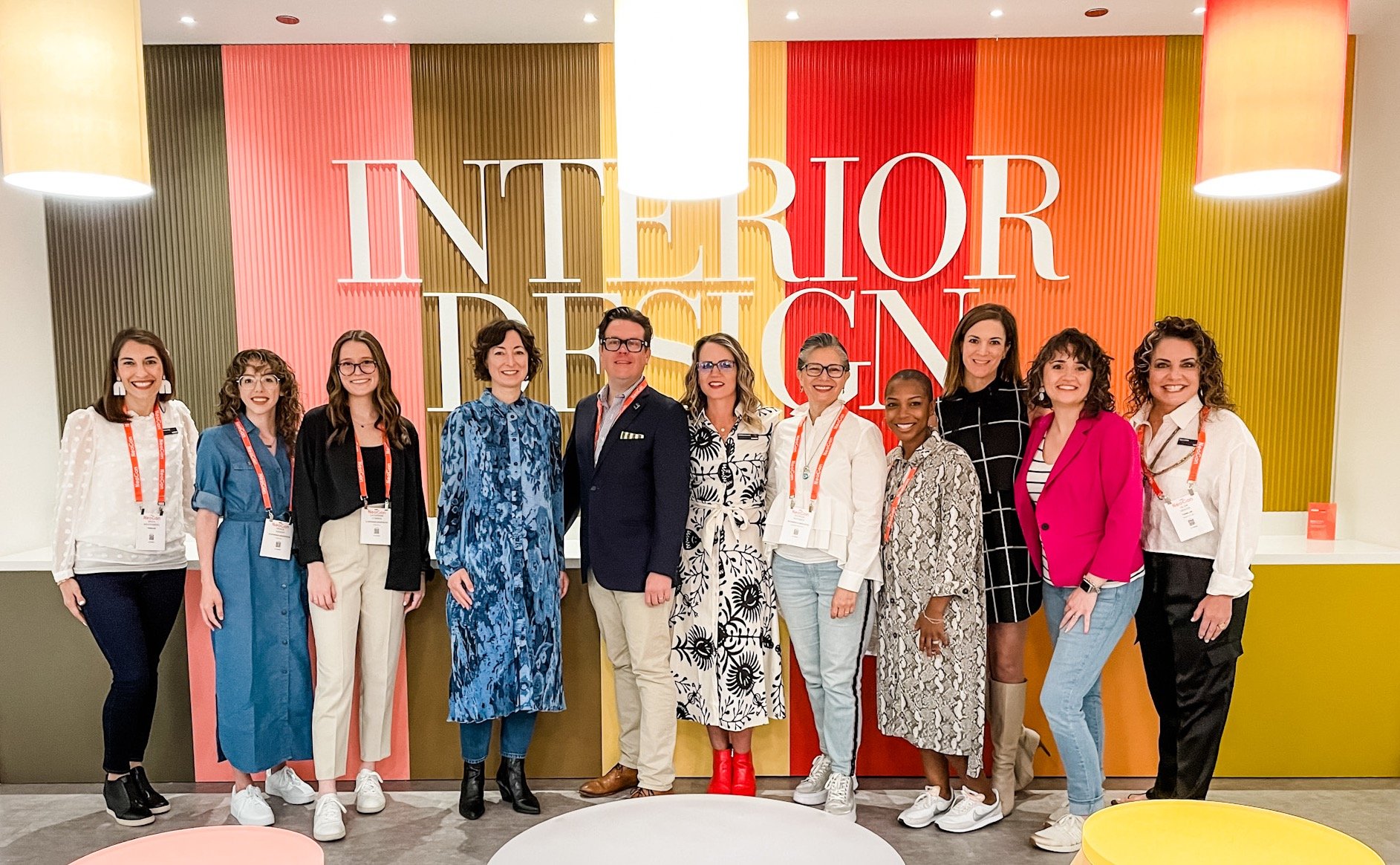 Group of people on the ThinkLab Trendspotters team standing in front of a multicolored wall with an Interior Design magazine sign