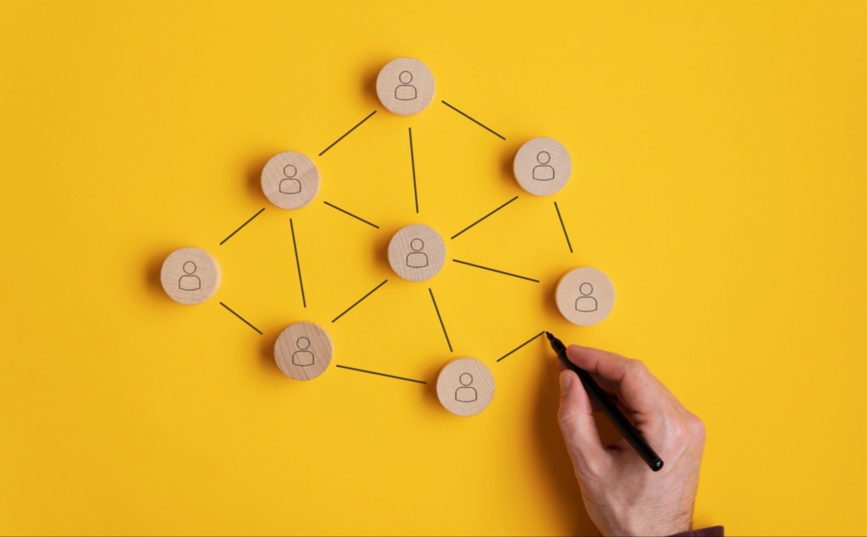 hand drawing connections between blocks with people symbols on a yellow background